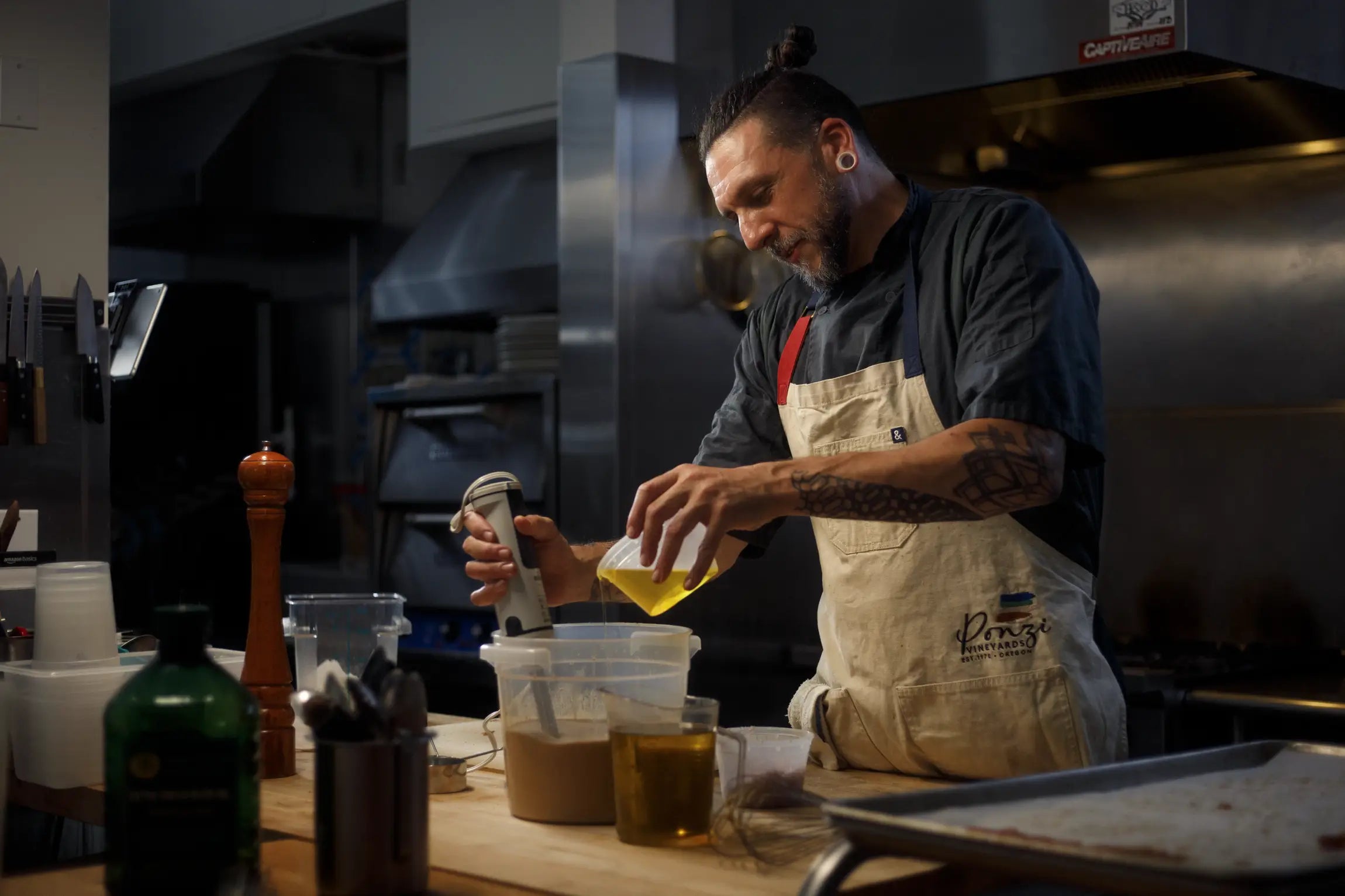 Person in a kitchen pouring liquid from a bottle into a container.