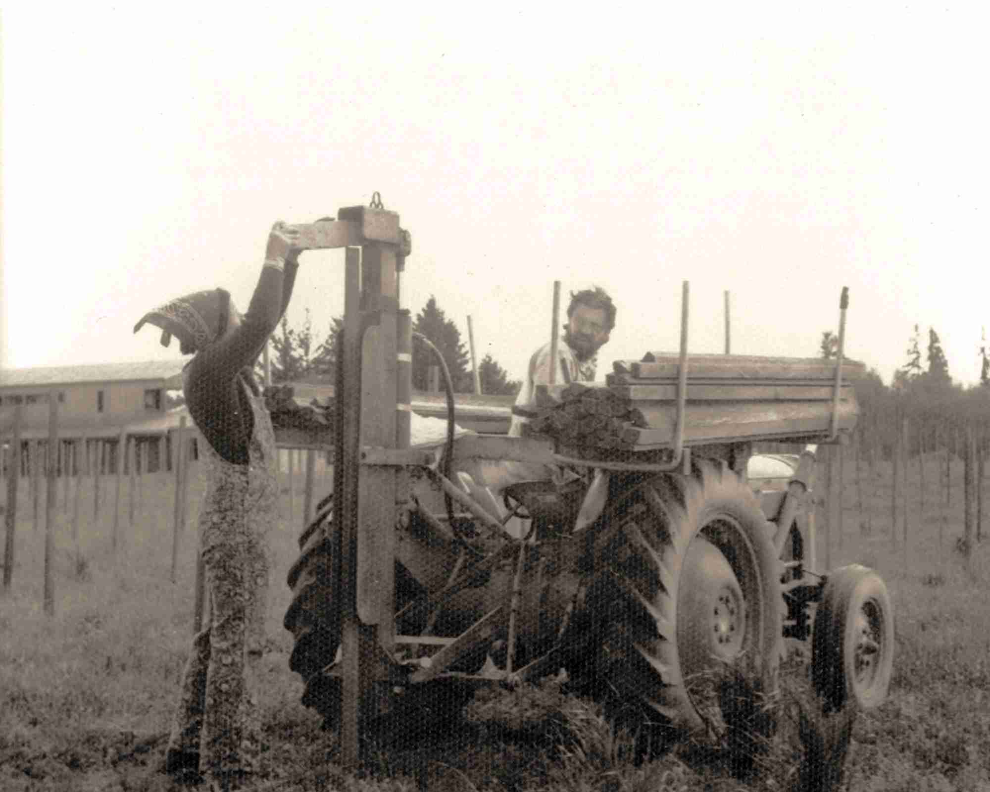 Vintage black and white photo of a person operating a tractor in an open field.